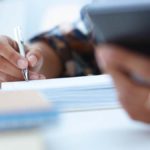 Business owner looking at a cell phone and writing.