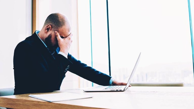 Stressed man with hand over eyes.