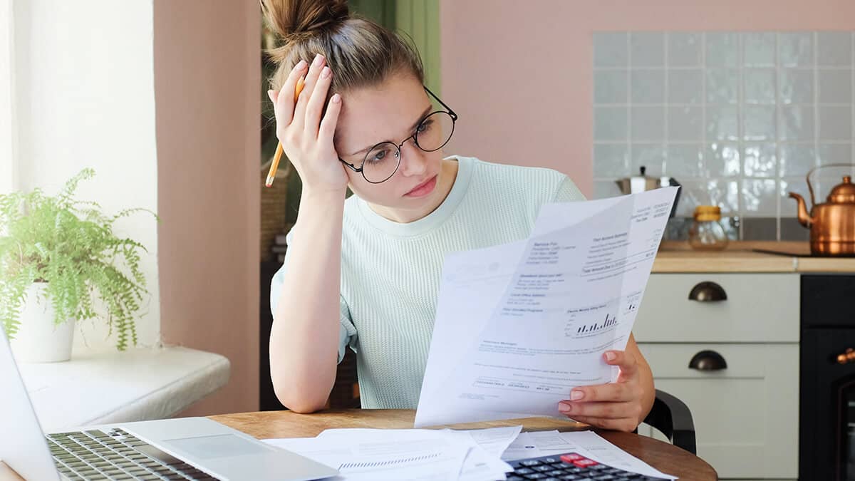 Stressed woman leaning on her hand and reading paper.