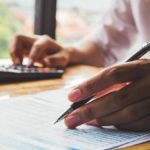 Business owner using calculator and writing.