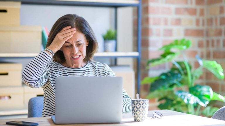 Stressed woman with hand on forehead.