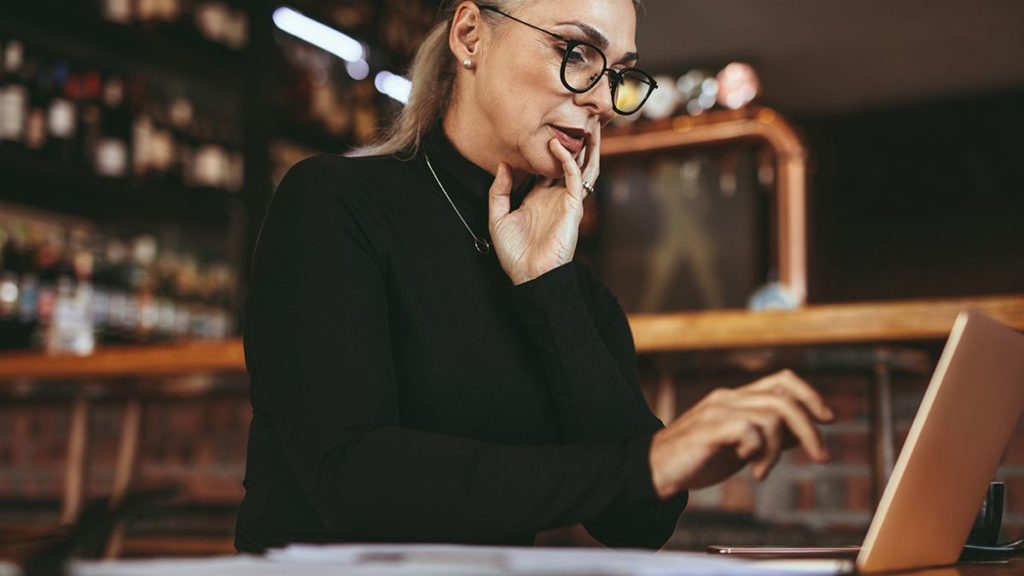 woman wearing glasses and turtleneck navigates her laptop