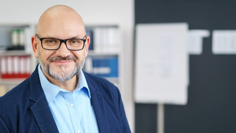 man wearing glasses smiling at the camera