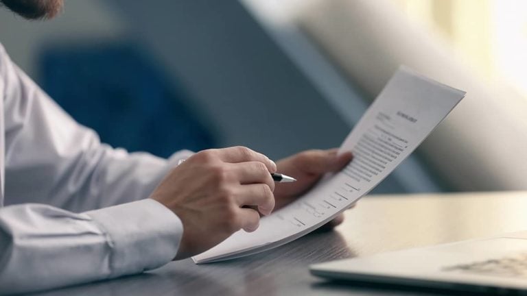 employer holding documents in one hand and a pen in the other