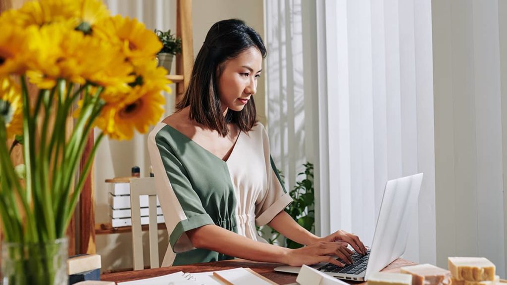 small business owner on her computer with yellow flowers next to her