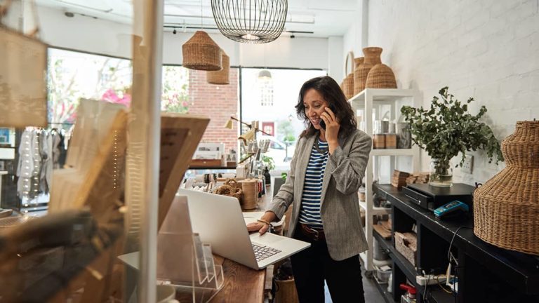 Smiling woman talking on her phone in her store