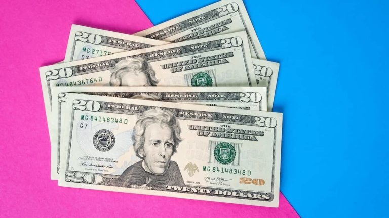 $20 bills stacked on a pink and blue background.