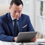 Man in a blue suit using a tablet.