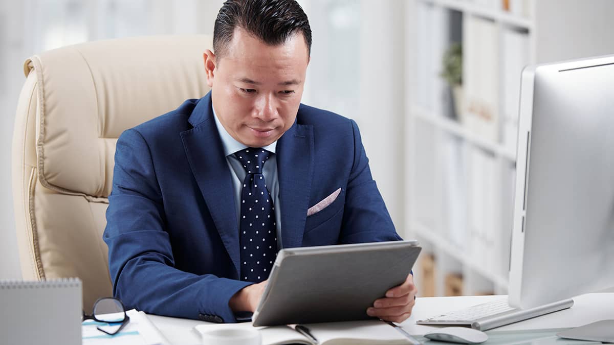 Man in a blue suit using a tablet.