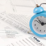 Blue alarm clock on paperwork.