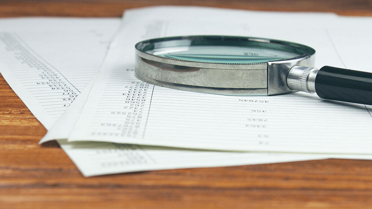 A magnifying glass on top of a few pieces of paper.