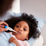 Little girl with a thermometer in her mouth.