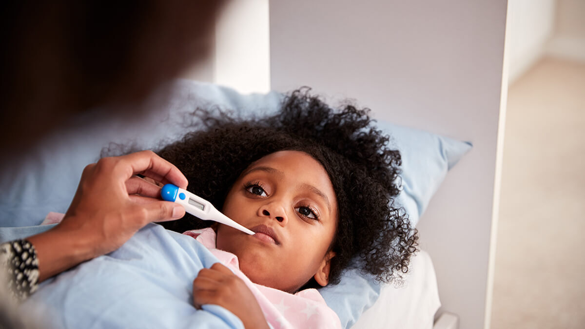 Little girl with a thermometer in her mouth.