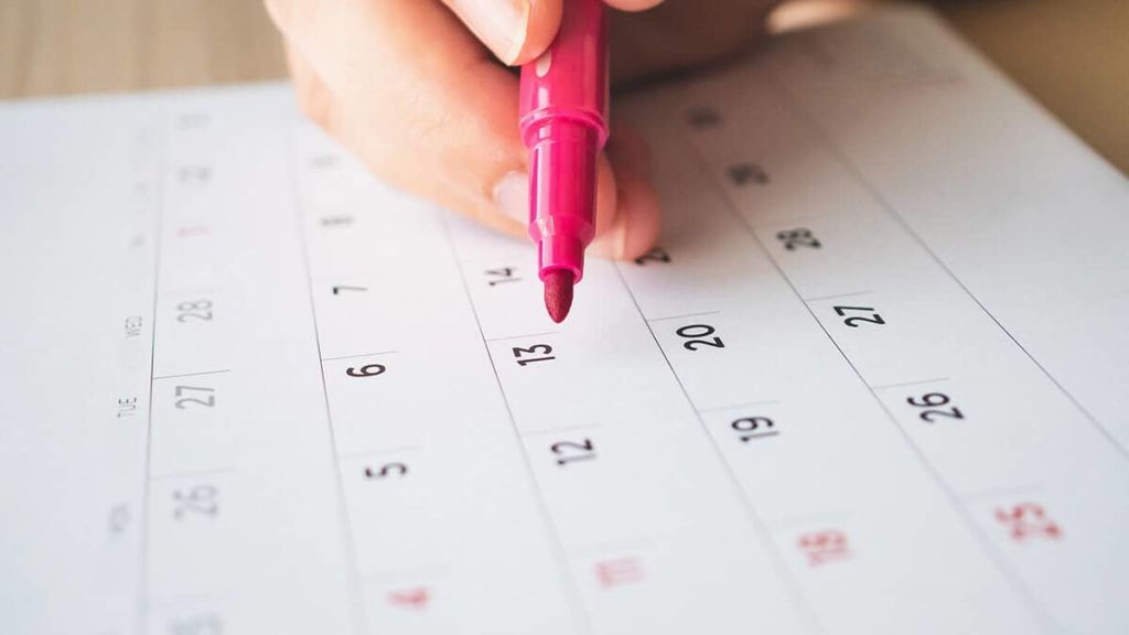 Employer holding a pink highlighter over a calendar marking 13 accounting periods.