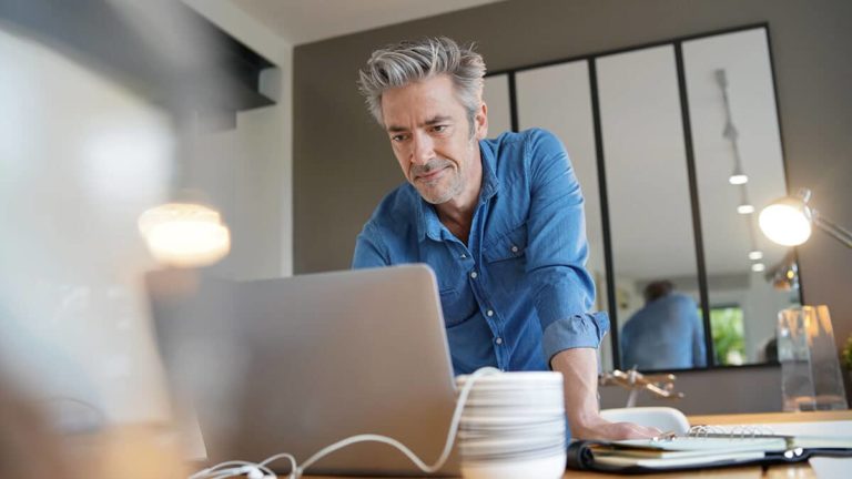 Standing man using a laptop.