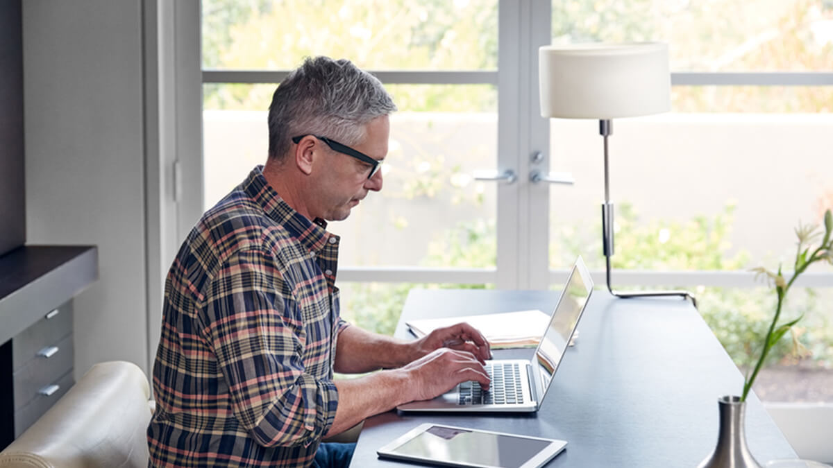 Man sitting at a desk and using a laptop.