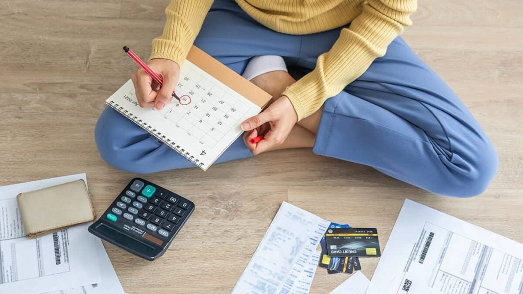 Woman circling a date on a calendar for a deferred payment.