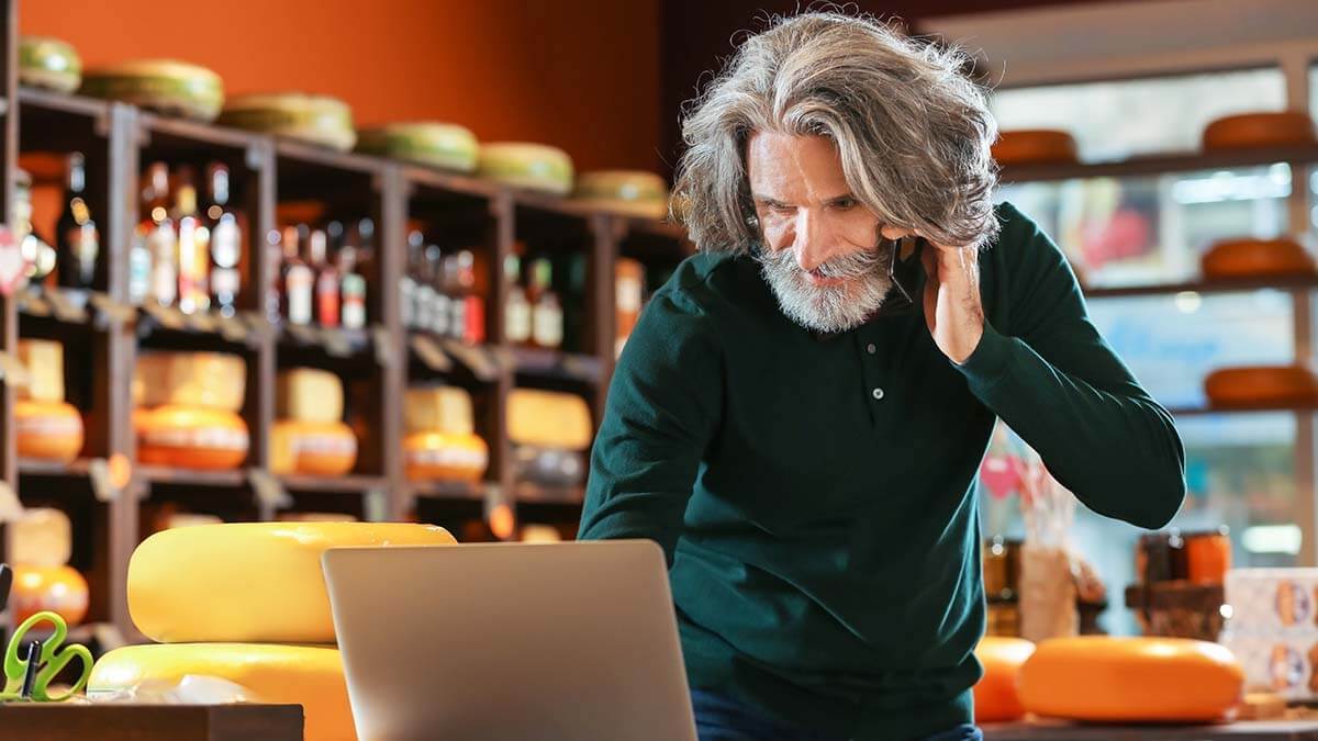 Older man on the phone and using a computer.
