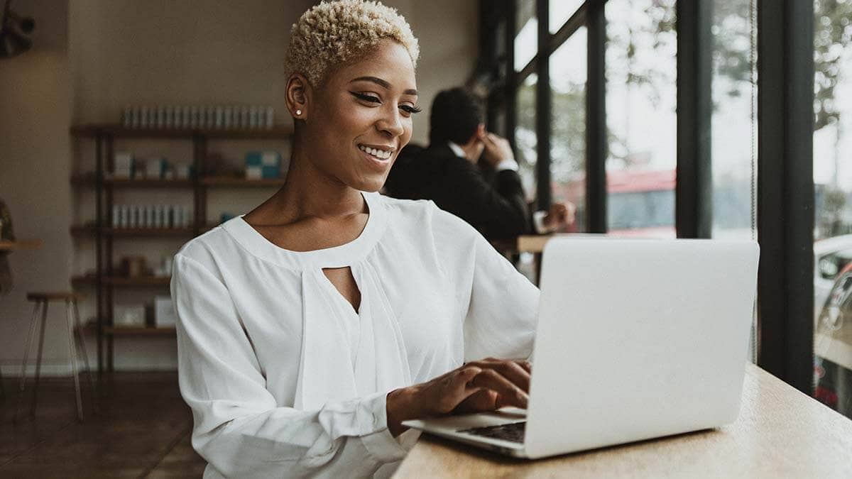 Smiling woman on the computer in public.