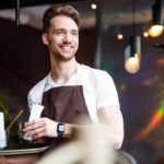 Barista smiling to someone off camera.
