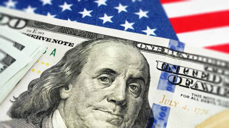 $100 bill with American flag in the background.