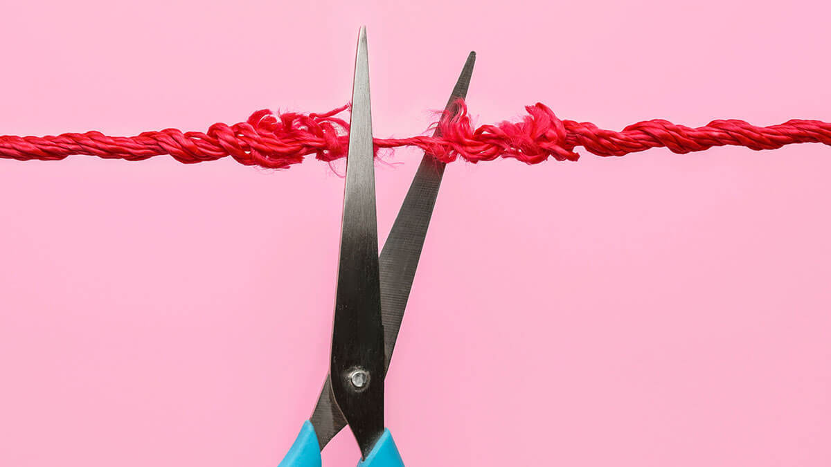 Scissors cutting a frayed red thread.