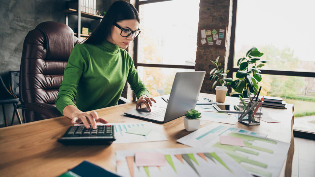 Woman reading more about full charge bookkeeping on a laptop.