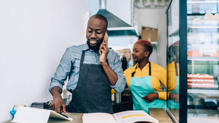 Bakery owner on the phone with an employee in the background.