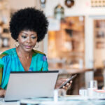 Woman using a laptop and cell phone.