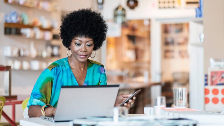 Woman using a laptop and cell phone.