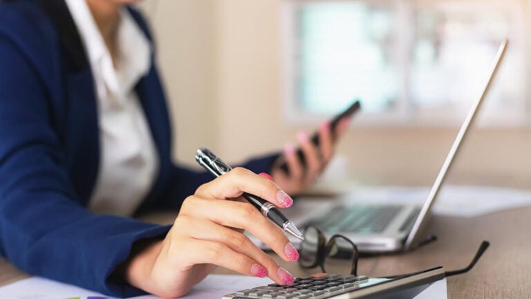 Woman using a cell phone and laptop.
