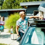 Family packing up a suitcase on the car for a trip.