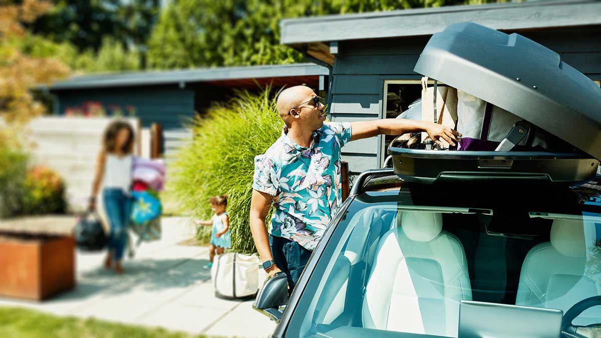 Family packing up a suitcase on the car for a trip.
