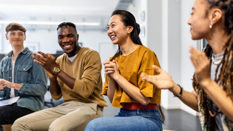 Employees in a circle clapping.