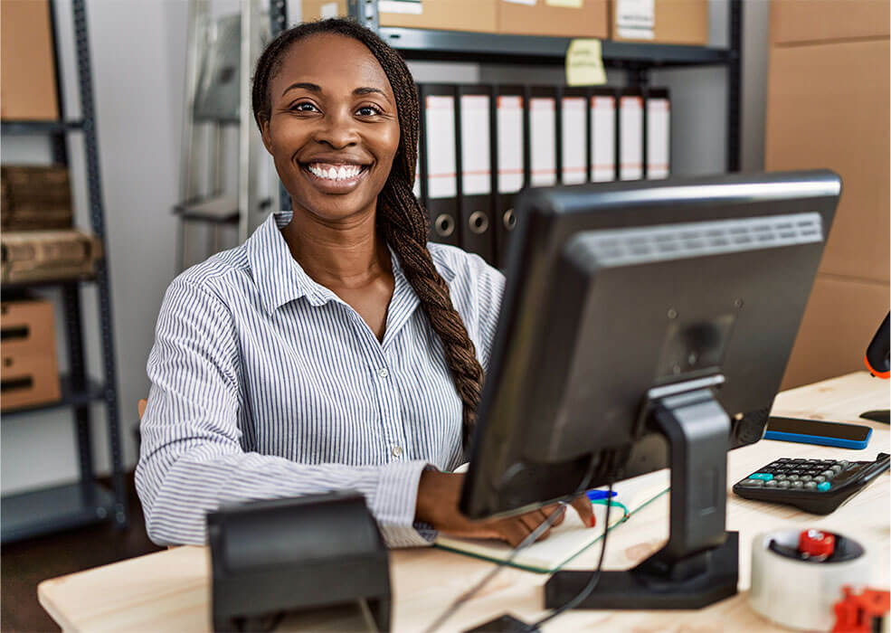 Happy woman using accounting software on desktop.