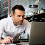 Business owner making correcting entries on laptop.