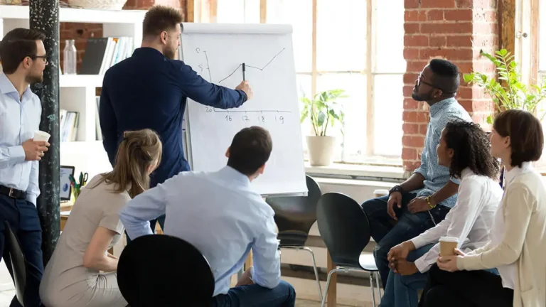Man presenting a line graph to a team of employees.