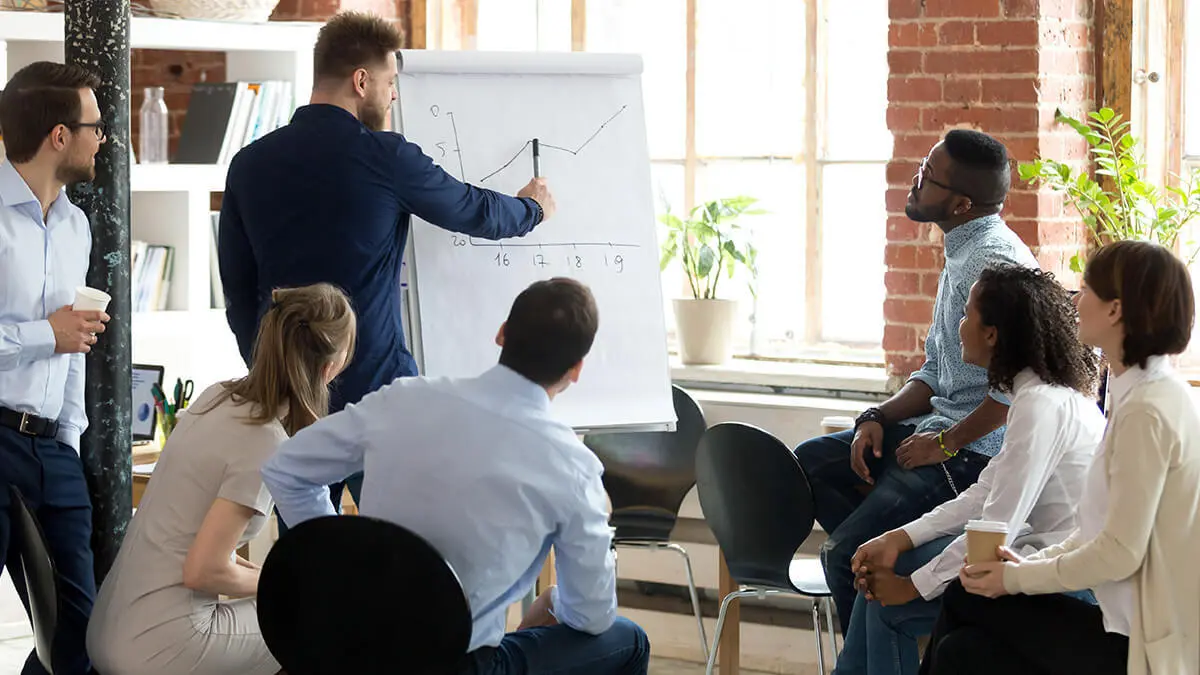 Man presenting a line graph to a team of employees.