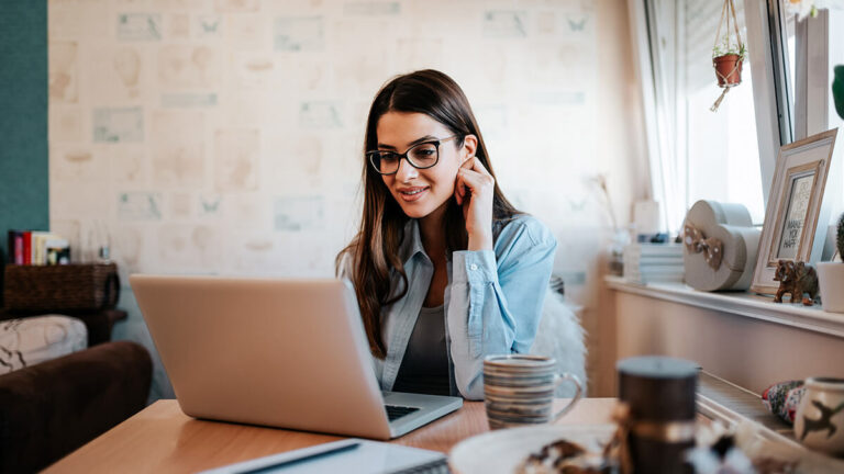 Woman looking at laptop with hand on the side of her head.