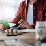 Business owner using a calculator and holding a notepad.