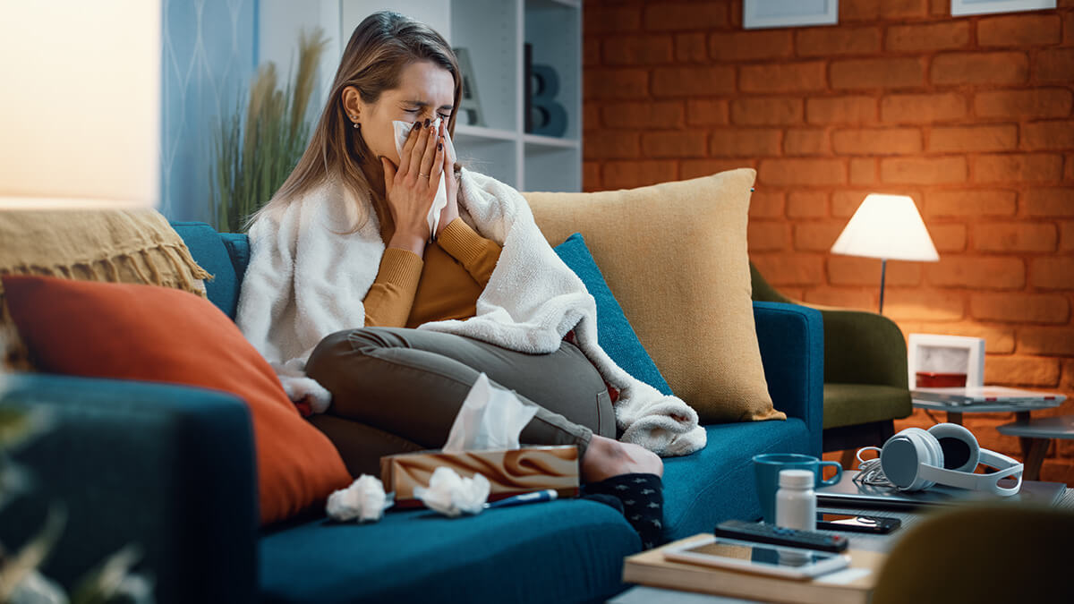Woman curled up on couch with blanket, using Arizona paid sick leave.