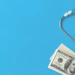 Money and stethoscope on blue background