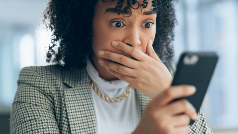 Shocked business owner looking at tax scams on her phone.