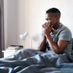 Man in bed taking advantage of Connecticut paid sick leave