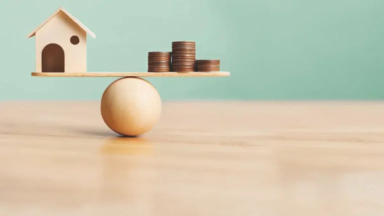 House and coins on a balance ball.