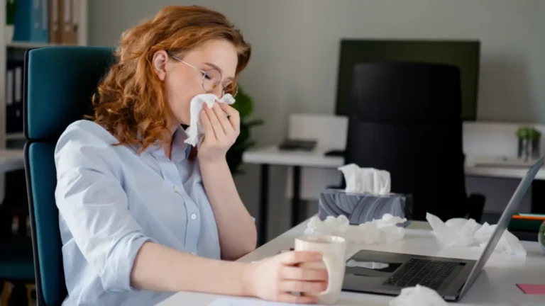 Employee blowing her nose at her desk.