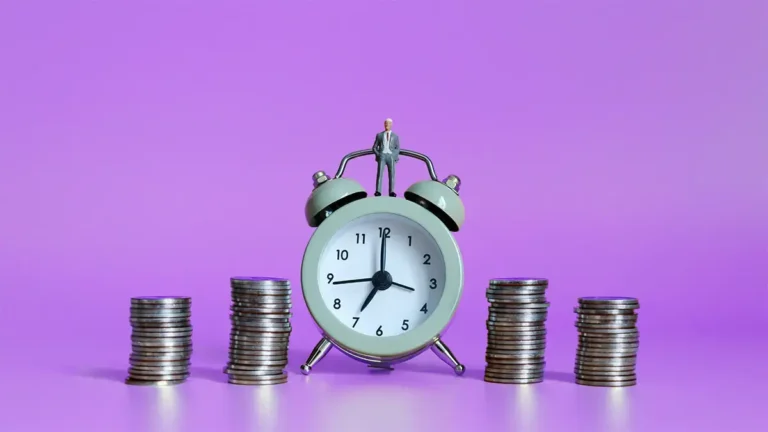 Alarm clock next to 4 stacks of coins.