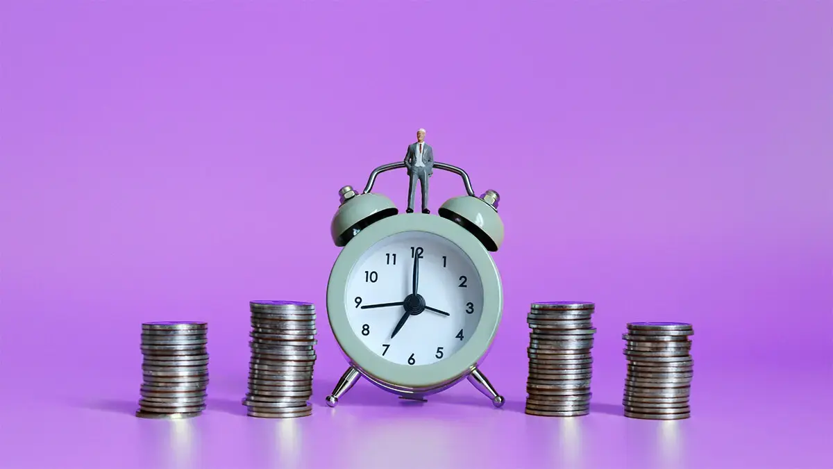 Alarm clock next to 4 stacks of coins.