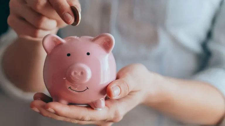 Woman putting a coin into a pink piggy bank, representing Trump Accounts.