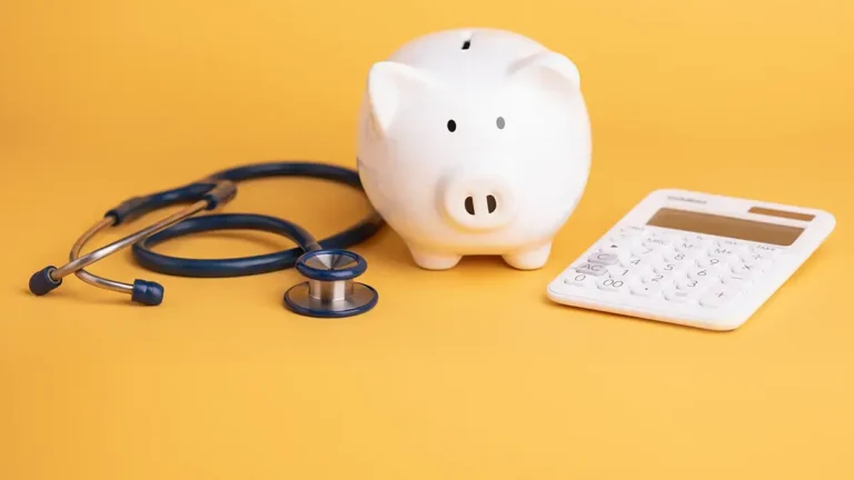 Piggy bank, stethoscope, and calculator on a yellow background.